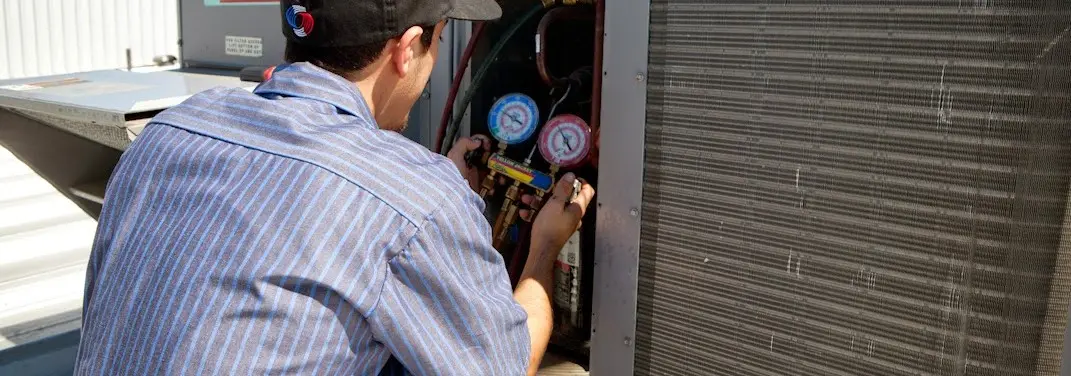 HVAC technician servicing a condenser unit in Del City